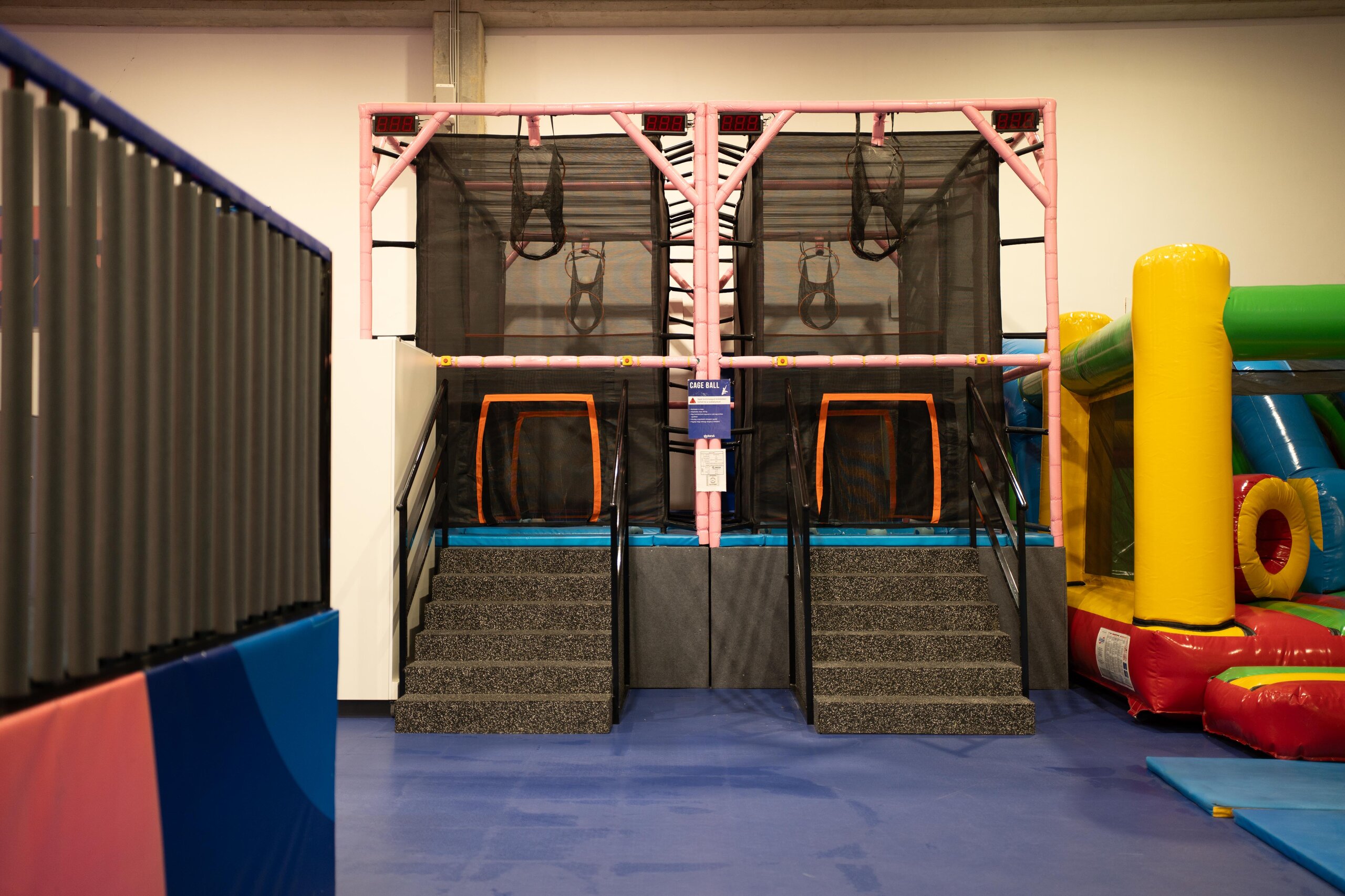 A Skyland Park Cageball zónája: két hálóval körülvett fülke narancssárga célgyűrűkkel és digitális pontszámlálóval